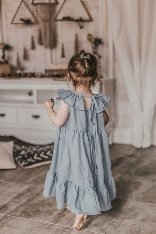 Toddler girl joyfully twirling in a blue ruffled dress indoors