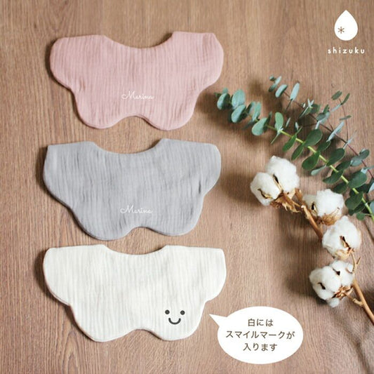 Three butterfly-shaped muslin bibs in pink, grey, and white

