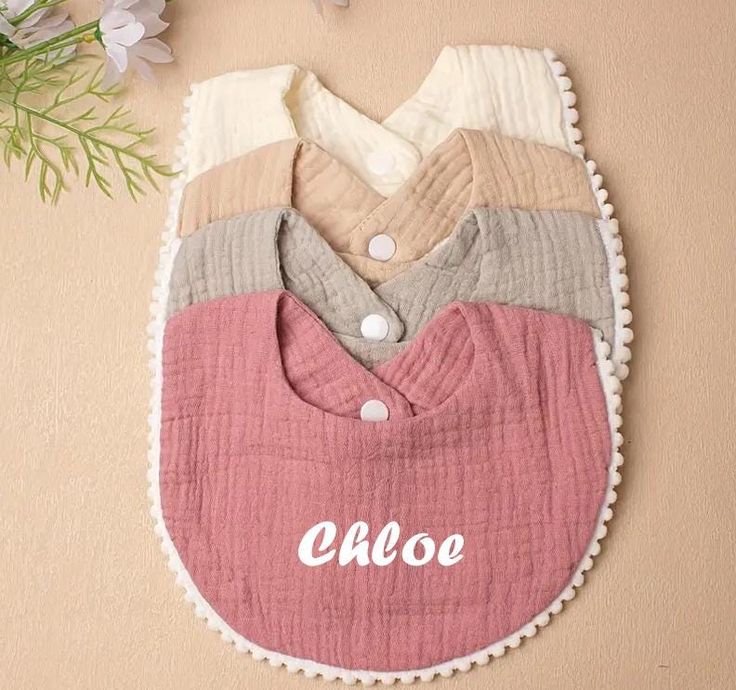 Personalized ruffle bibs for newborn girls hanging on pastel wall


