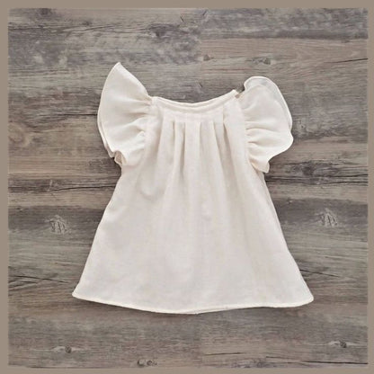 featuring short puff sleeves and gathered pleats, laid flat on a white bedsheet.