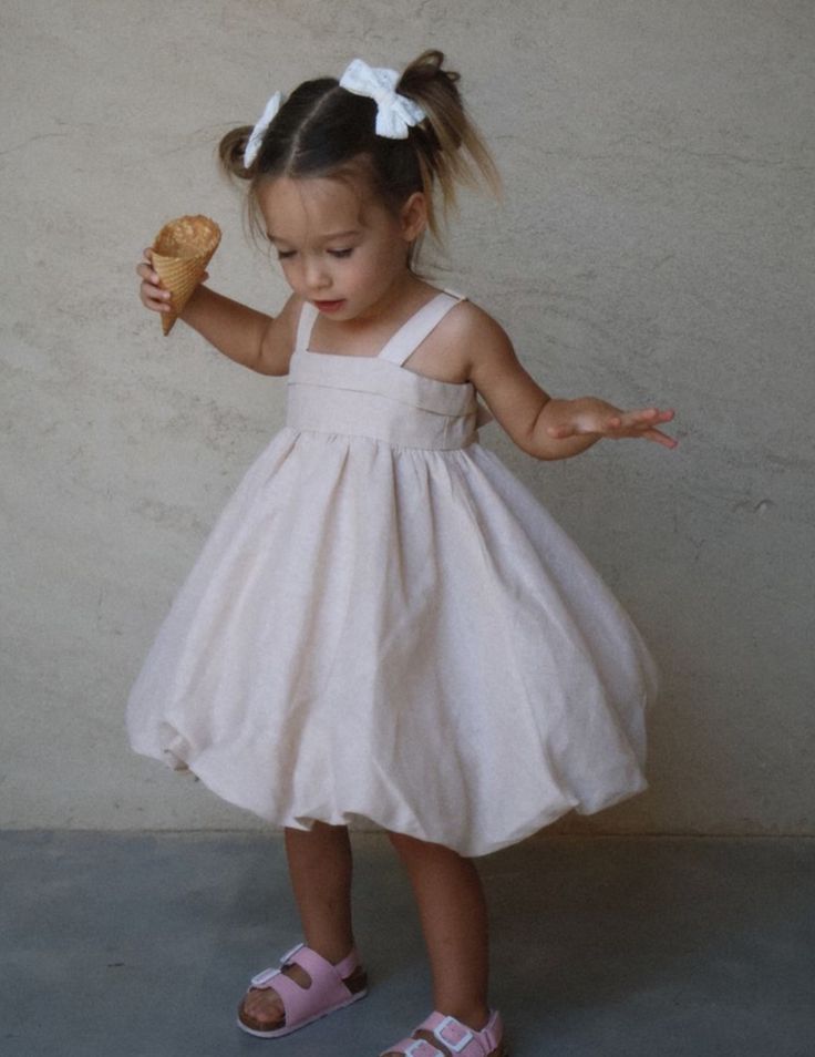 Baby girl in brown bow-back dress standing inside a van
