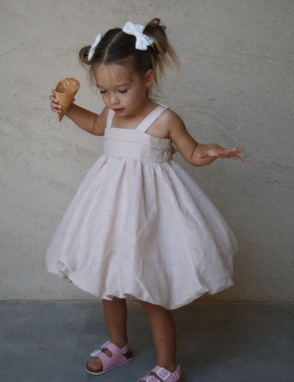 Baby girl in brown bow-back dress standing inside a van