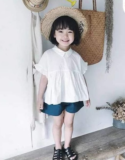Toddler girl in white flutter top and navy shorts
