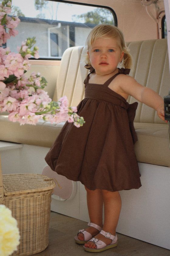 Girl posing in stylish brown baby dress with pink sandals
