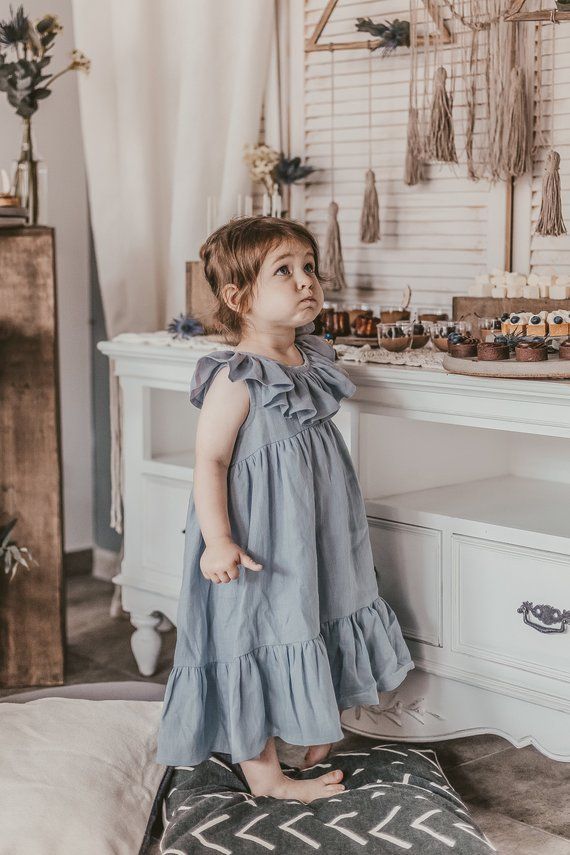 Little girl wearing soft blue cotton ruffle dress in a cozy room